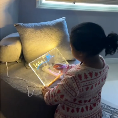 Child enjoying a glowing LED drawing board